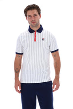 A man modeling a white short-sleeve polo shirt with thin navy vertical pinstripes, a navy collar, a red three-button placket, and a small red and blue chest logo, paired with navy pants against a white studio background.