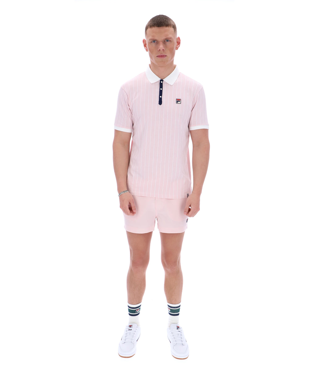Man wearing a pink polo shirt and shorts set on a white background