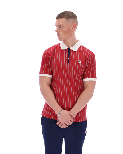 Man wearing a red striped polo shirt with a white collar and blue pants on a white background