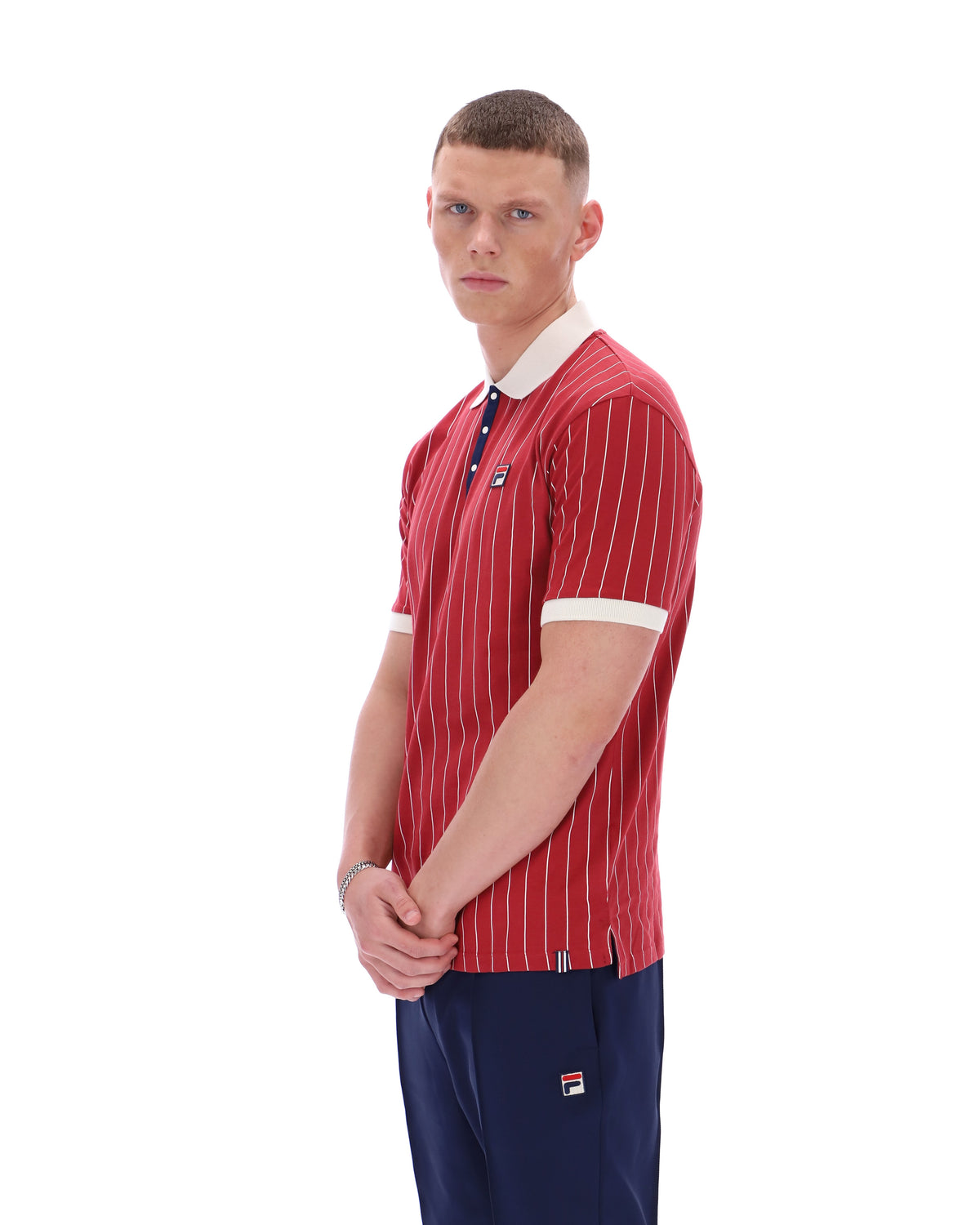 Man wearing a red striped polo shirt and navy pants with a brand logo on a white background