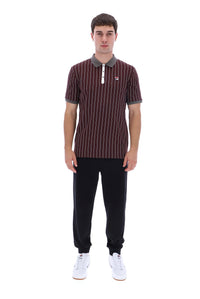 A man modeling a short-sleeve polo shirt with thin vertical stripes in dark red and brown, featuring a gray collar and white buttons, paired with black pants and white sneakers against a plain white background.