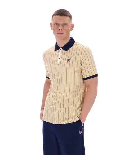 Man wearing a beige and navy striped polo shirt with matching pants on a white background