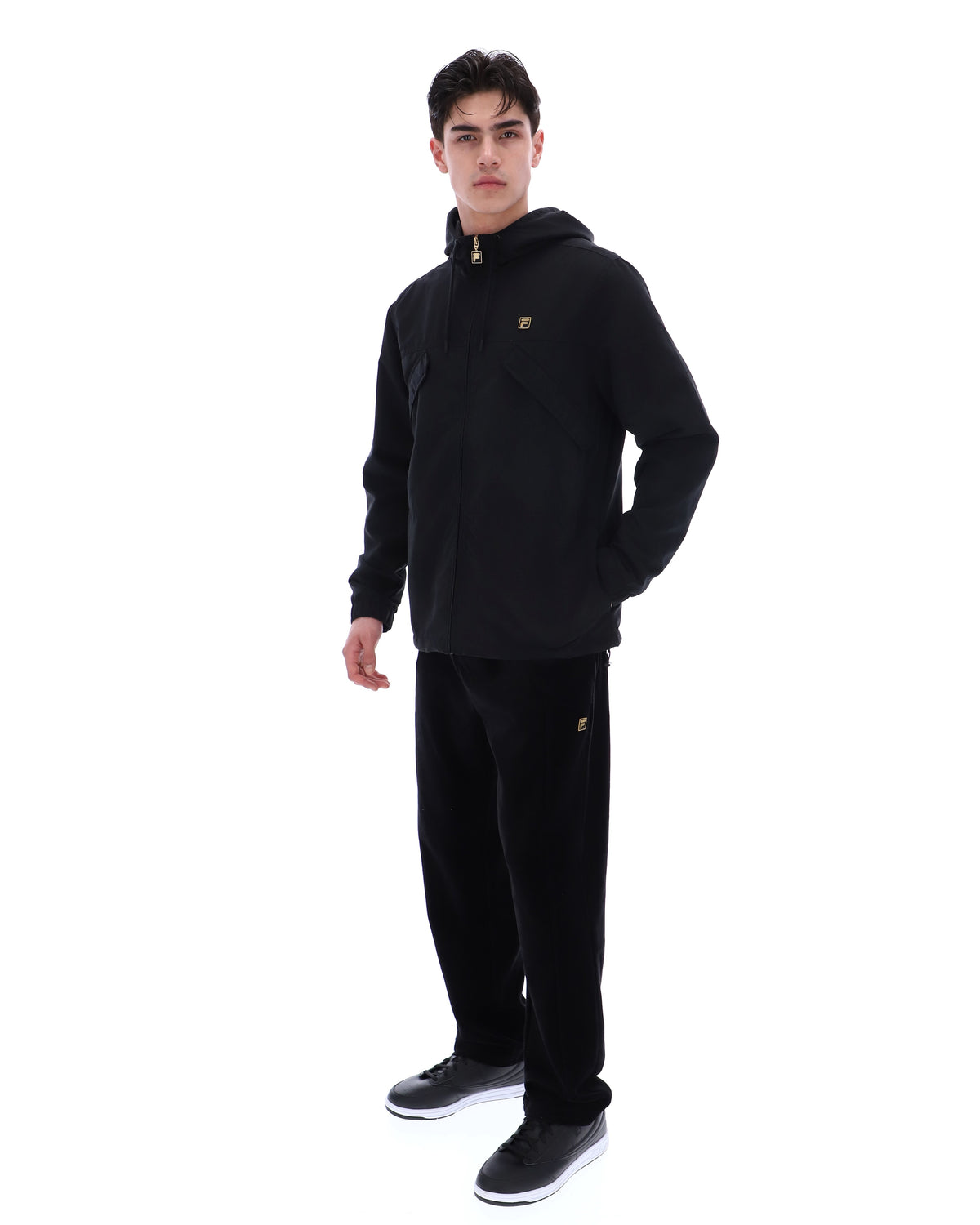 Person wearing a black hoodie and pants with a brand logo on a white background