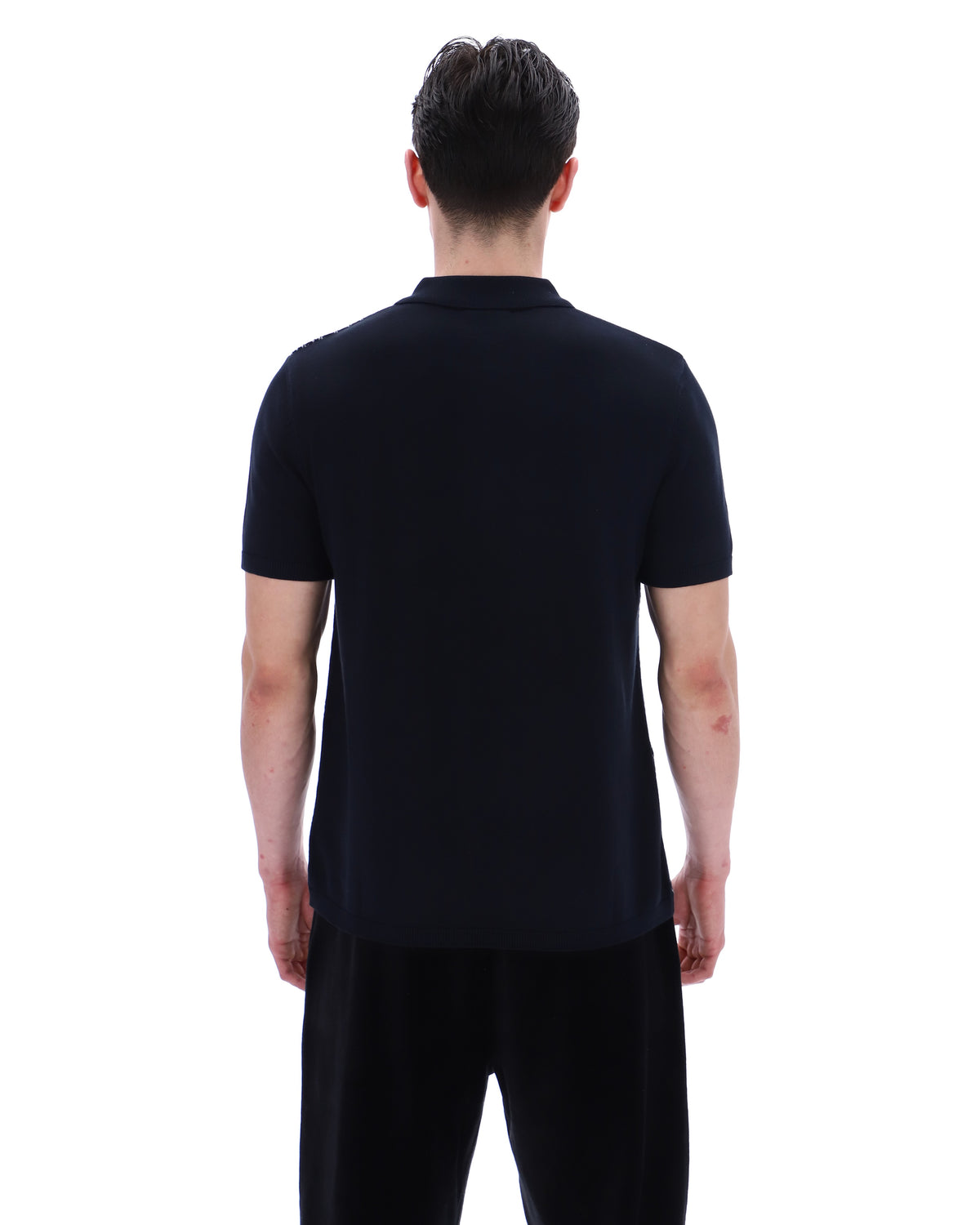 Person wearing a black polo shirt and pants on a white background