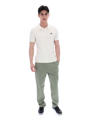 Man wearing a white polo shirt and green pants on a white background