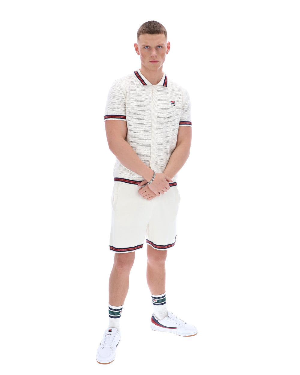 Man wearing a white polo shirt and shorts set with red accents on a white background