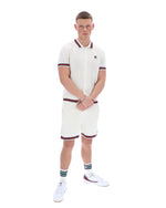 Man wearing a white polo shirt and shorts set with red accents on a white background