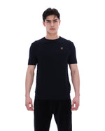 Man wearing a black t-shirt with a small FILA Gold logo on the chest on a white background
