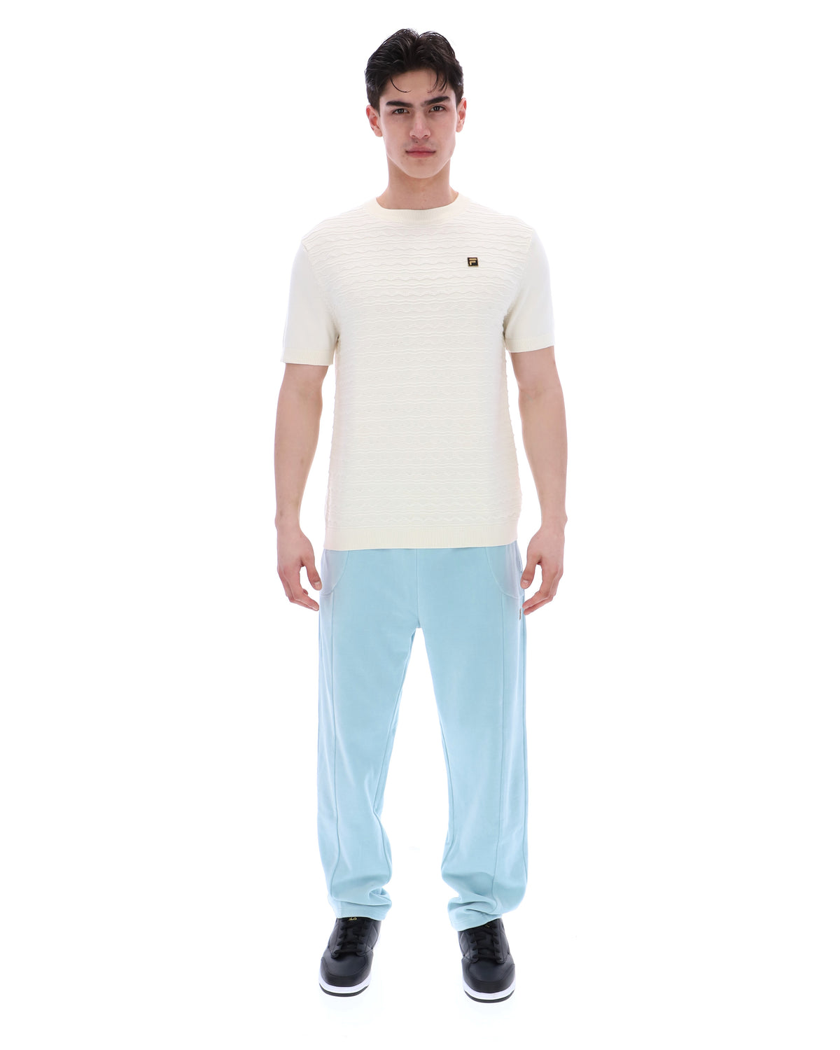 Man wearing a white t-shirt and light blue pants on a white background