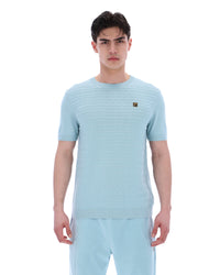 Man wearing a light blue textured t-shirt and pants on a white background