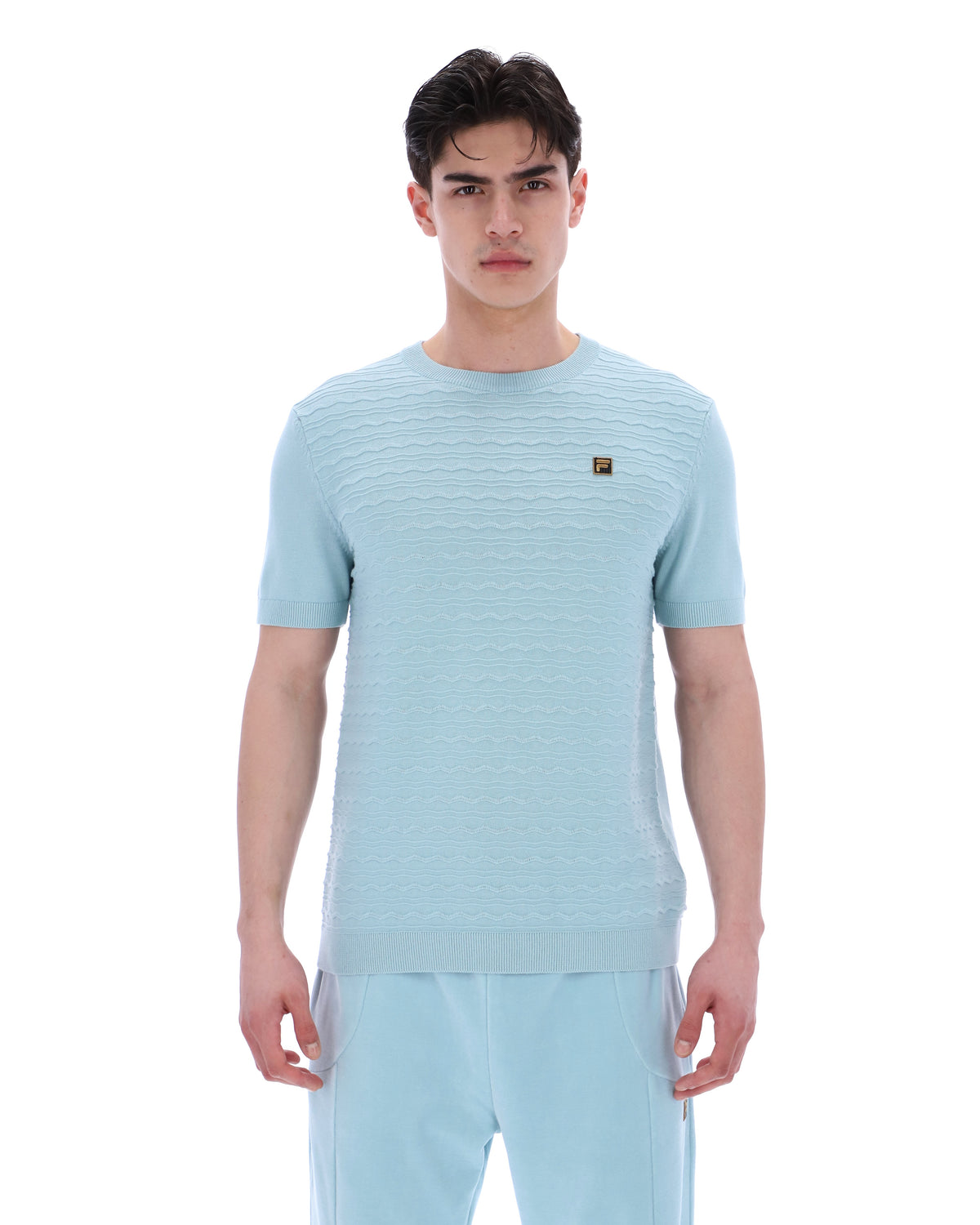 Man wearing a light blue textured t-shirt and pants on a white background