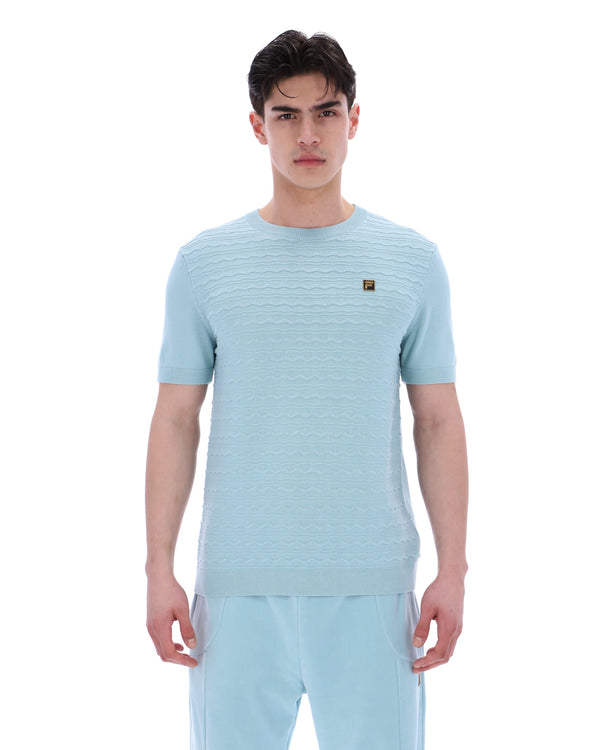 Man wearing a light blue textured t-shirt and pants on a white background