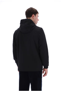 A man viewed from the back wearing a black hooded jacket and dark pants against a plain white studio background.