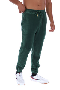 A person wearing dark green jogger sweatpants with a drawstring waist and elastic cuffs, paired with white sneakers, shown against a plain white background.