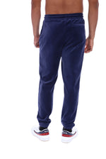 A person shown from the back wearing navy blue jogger sweatpants and white sneakers with red and black accents, against a plain white background.