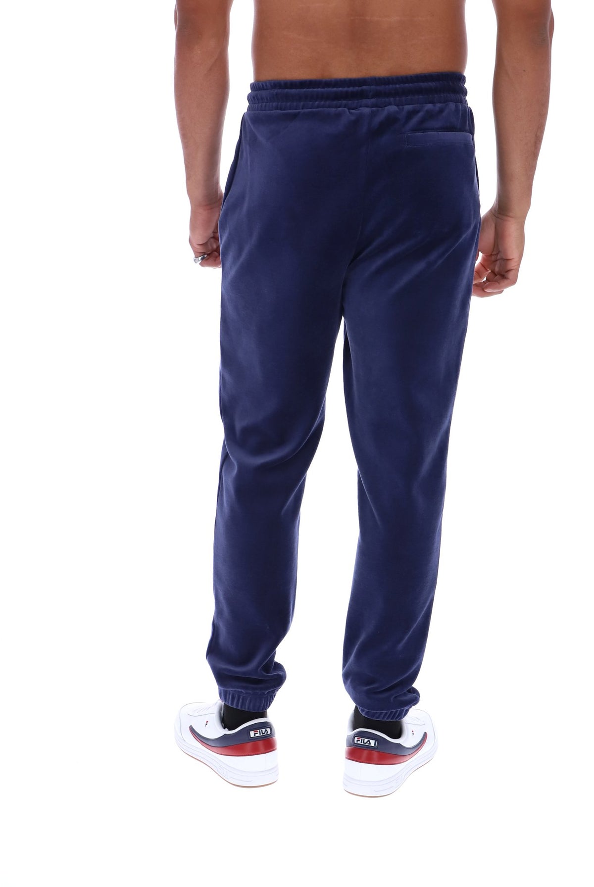 A person shown from the back wearing navy blue jogger sweatpants and white sneakers with red and black accents, against a plain white background.
