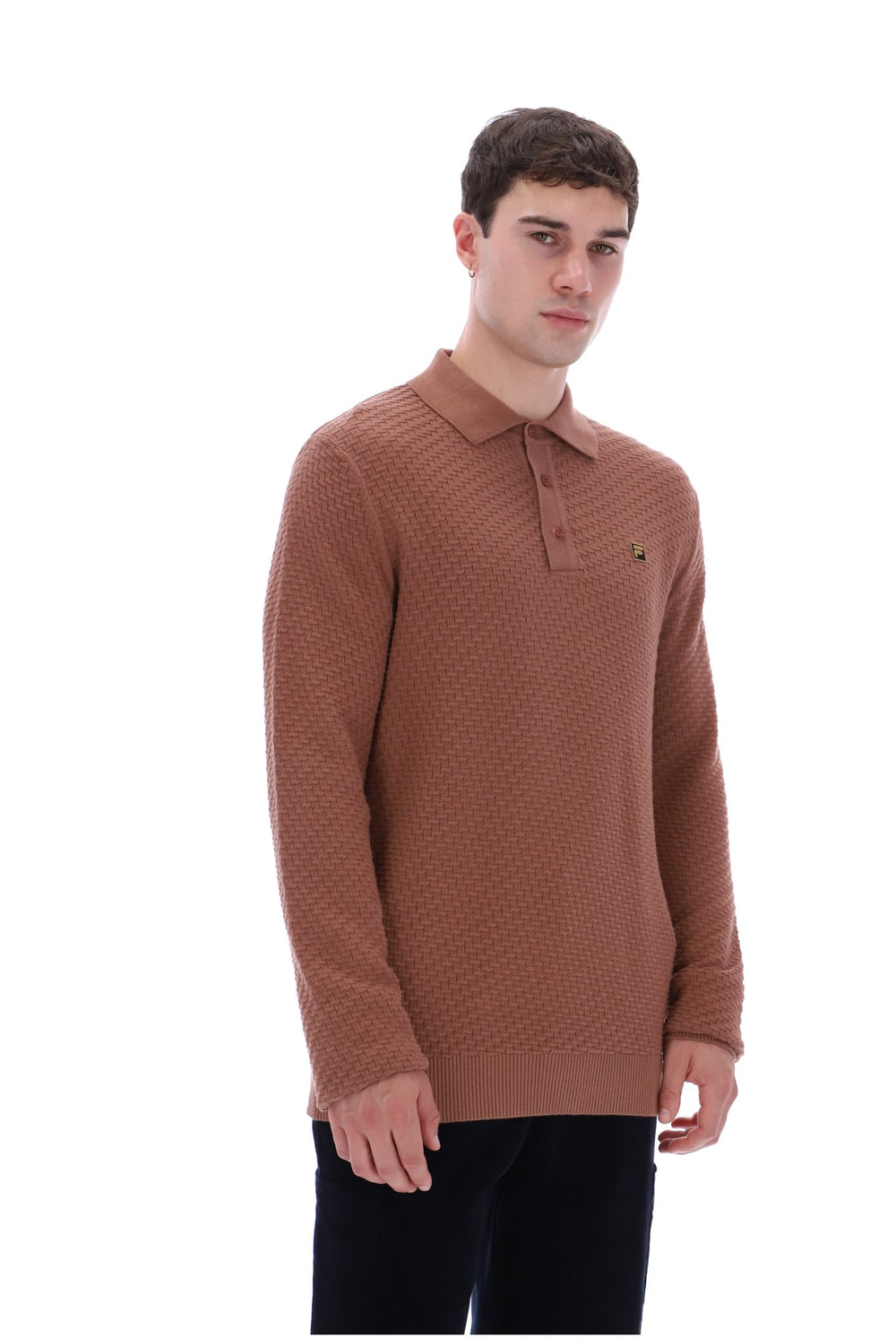 A man wearing a textured brown knit polo sweater with a small embroidered green and yellow crocodile logo on the chest, paired with black trousers, against a plain white background.