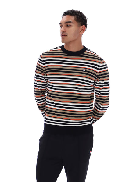 A man wearing a long-sleeve crewneck sweater with horizontal stripes in black, white, and tan, paired with black sweatpants, photographed against a solid white background.