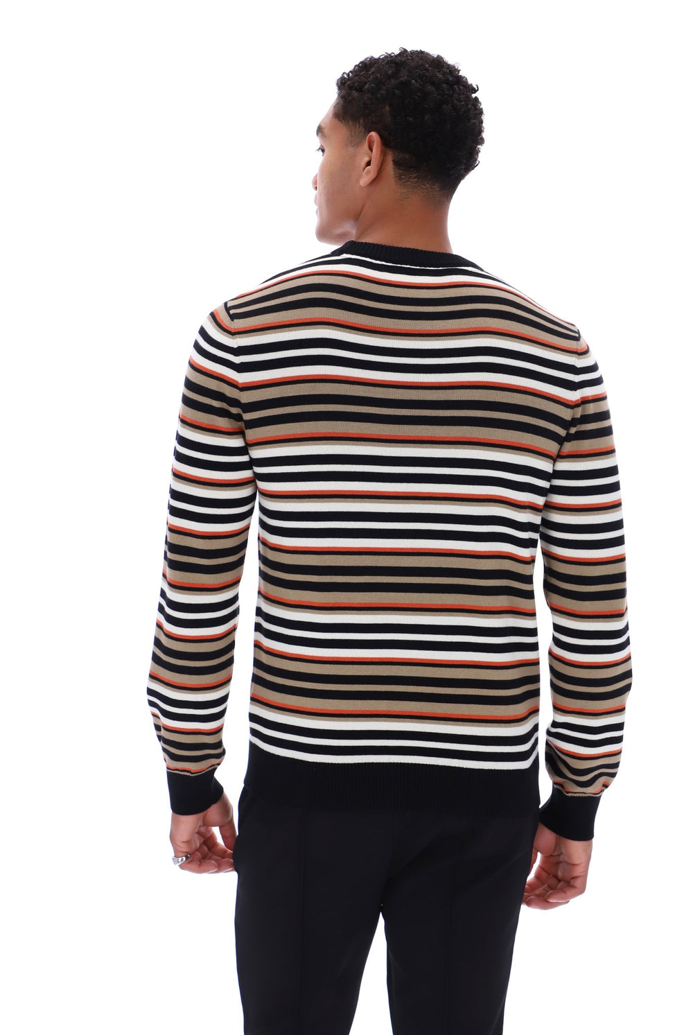 A man viewed from the back wearing a long-sleeve knit sweater with horizontal stripes in black, white, and a warm tan/beige color, paired with black pants, against a plain white background.