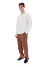 Woman wearing a gray long-sleeve top and black pants on a white background