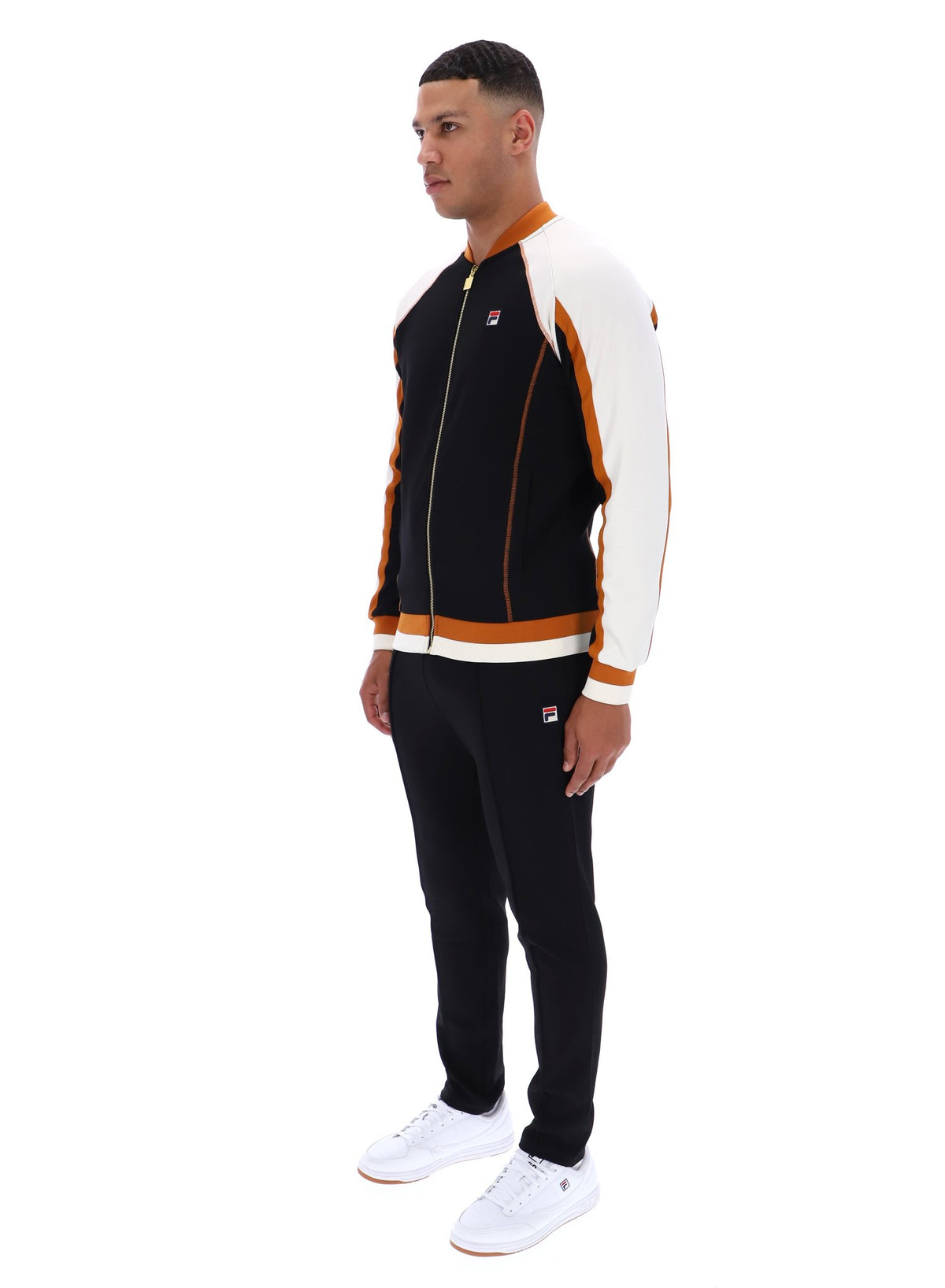 Man wearing a black and white tracksuit with orange accents on a white background