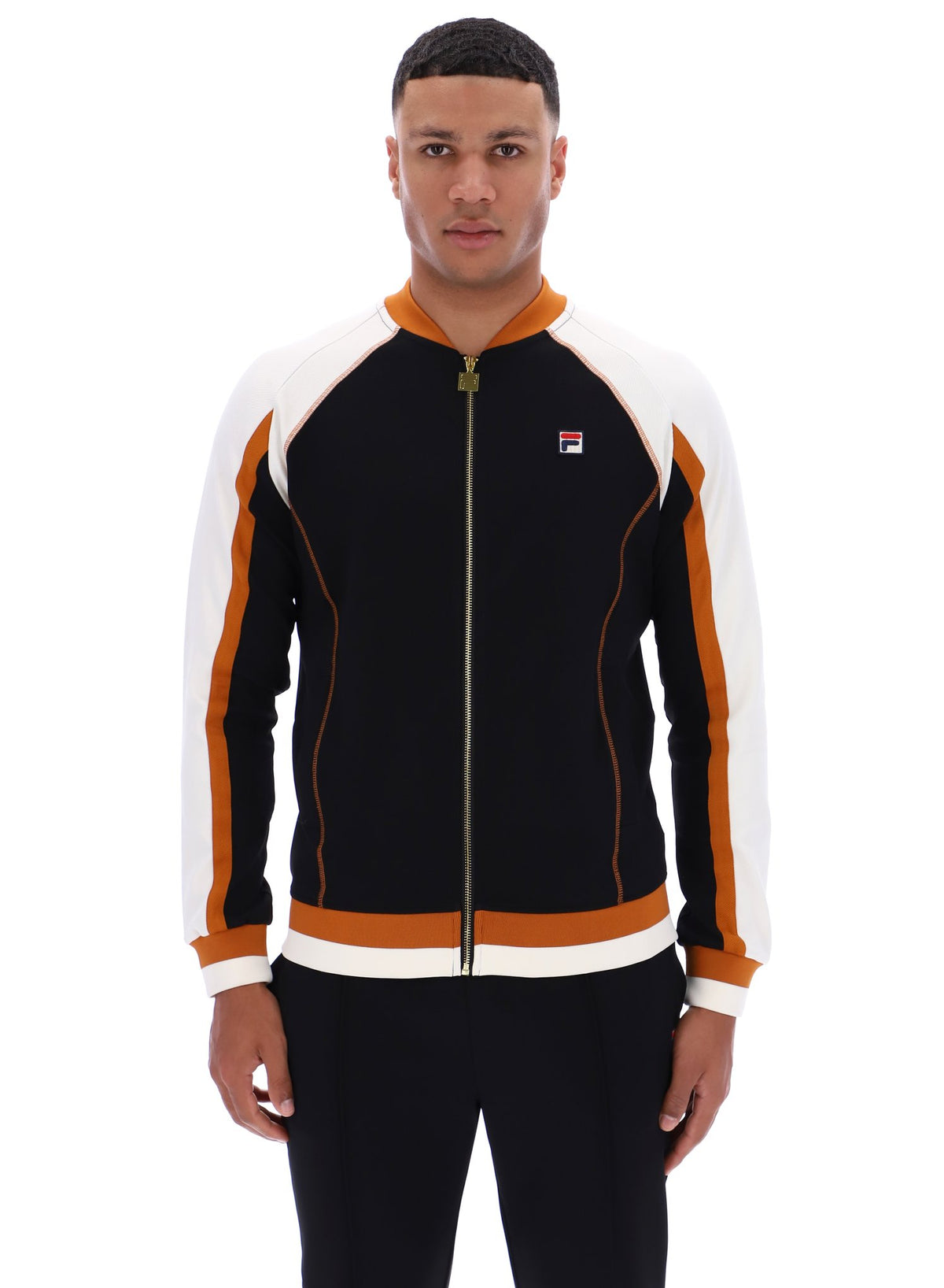 Man wearing a black and orange tracksuit with a visible FILA logo on a white background
