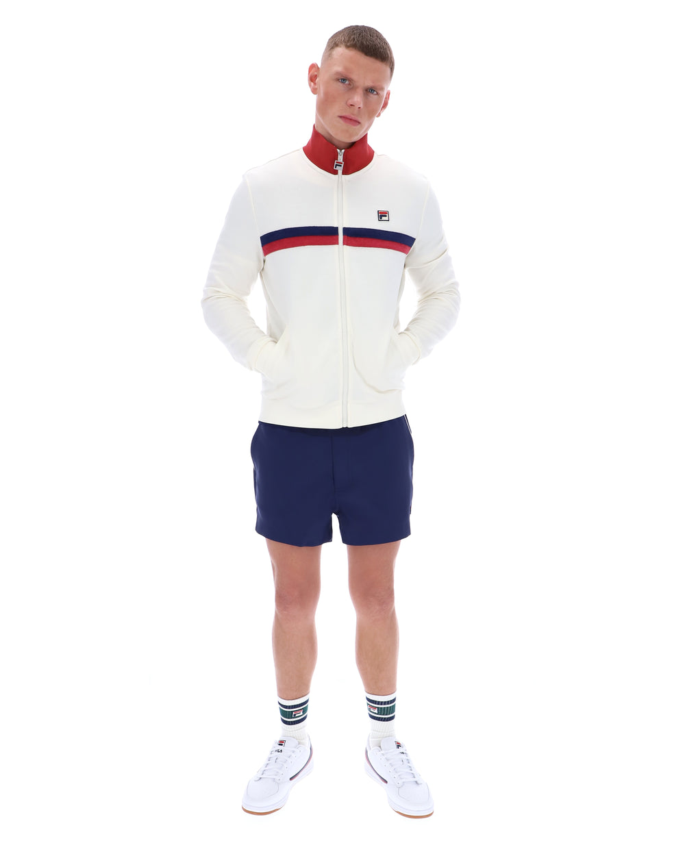 Man wearing a white sweater with red and blue stripes and navy shorts on a white background