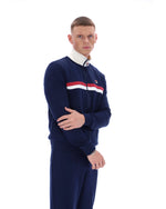 Man wearing a navy tracksuit with a white collar and red and white stripe on a white background