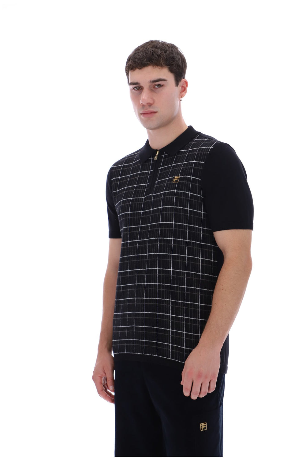 A man modeling a black short-sleeve polo shirt with a white windowpane plaid pattern on the front panel and a small gold logo on the chest, set against a plain white background.