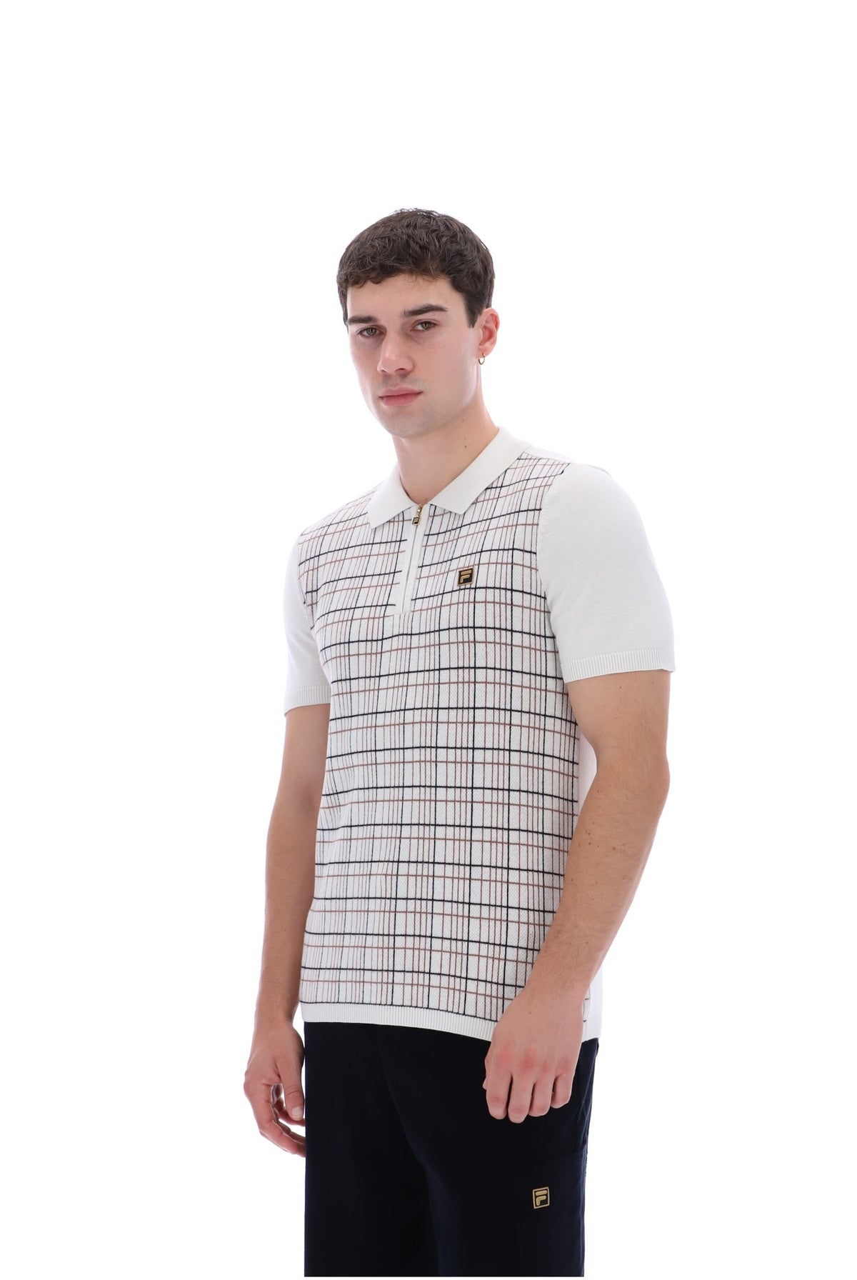 A man wearing a white short-sleeve polo shirt with a beige and brown plaid knit vest overlay, paired with black pants, against a solid white background.