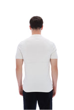 A man viewed from the back wearing a fitted short-sleeve polo shirt in off-white and dark trousers, against a plain white studio background.