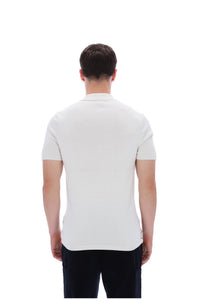 A man viewed from the back wearing a fitted short-sleeve polo shirt in off-white and dark trousers, against a plain white studio background.