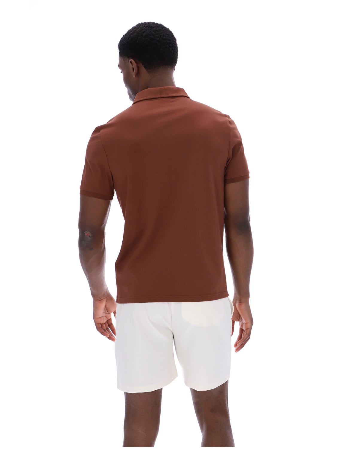 Man wearing a brown polo shirt and white shorts on a white background