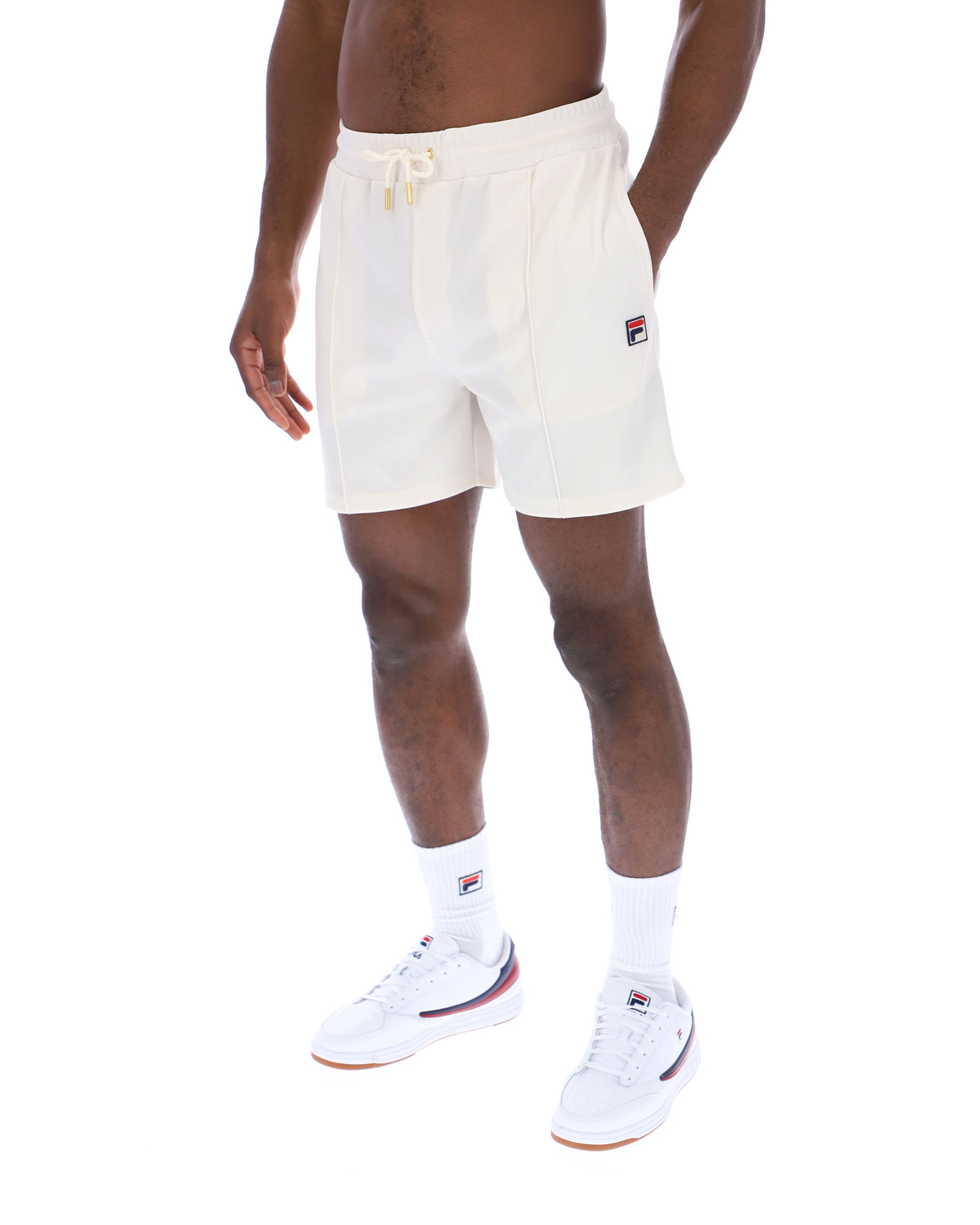 Displays a model wearing the Gardenia 'FILA' branded Eusebio Pin-Tuck Shorts