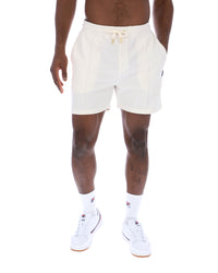Displays a model wearing the Gardenia 'FILA' branded Eusebio Pin-Tuck Shorts