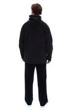 A man viewed from behind wearing a black hooded jacket and black pants against a plain white background.