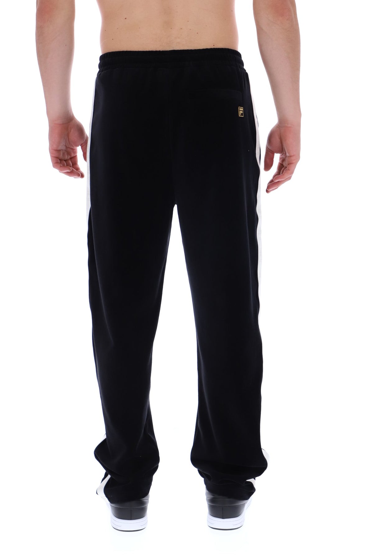 Black sweatpants with white side stripes and a small gold logo on the back pocket, shown on a model from the back against a white background.