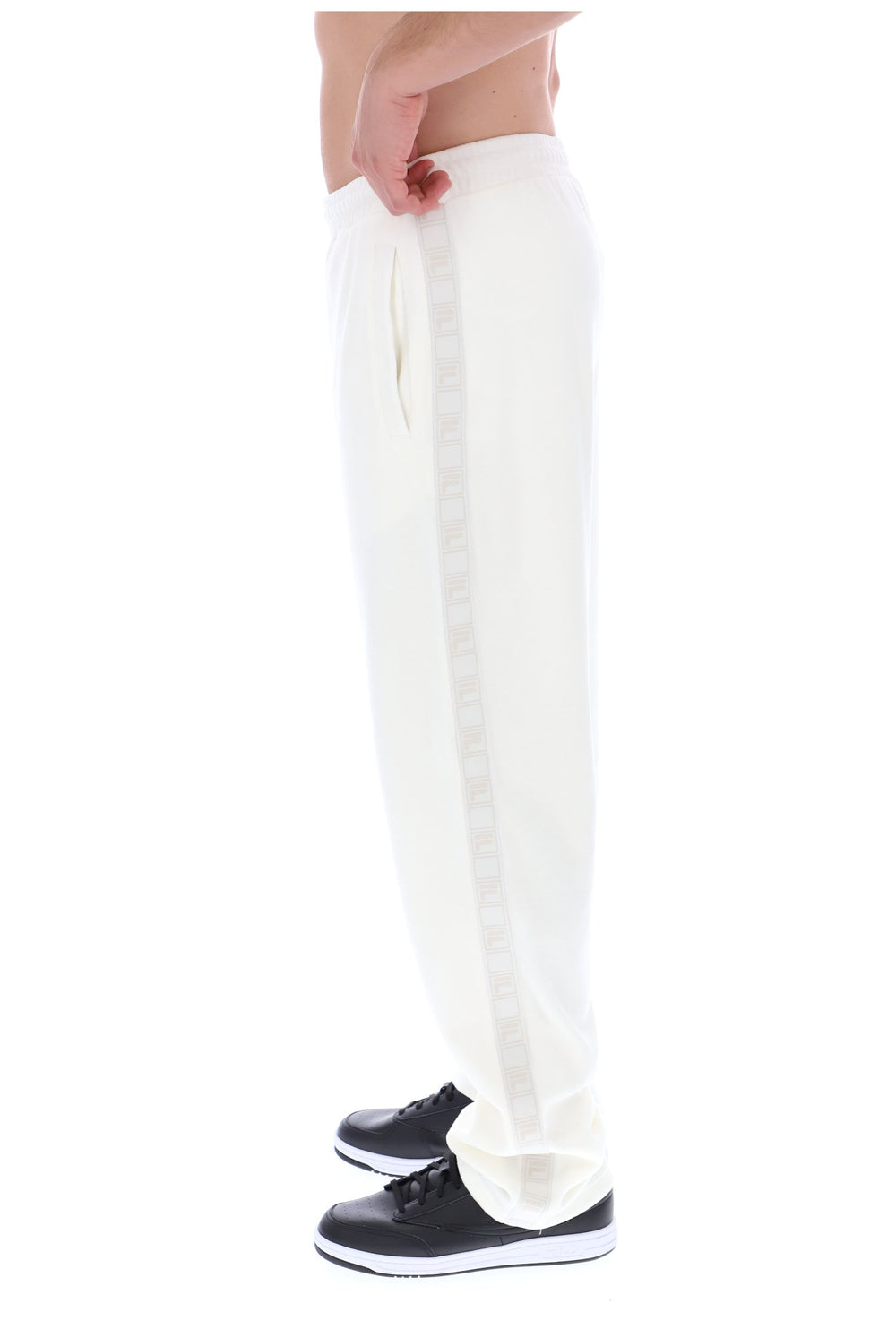 Displays a model wearing the White 'FILA' branded Down Fario Velour Track Pant