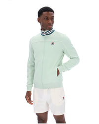 Person wearing a light green jacket with a brand logo on a white background