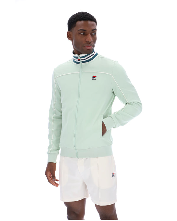 Person wearing a light green jacket with a brand logo on a white background