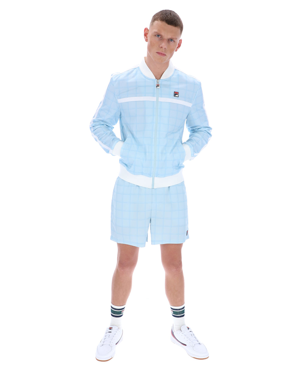 Man wearing a light blue tracksuit with white accents on a white background