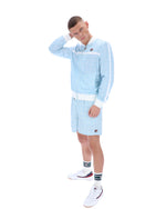 Person wearing a light blue tracksuit with white accents on a white background