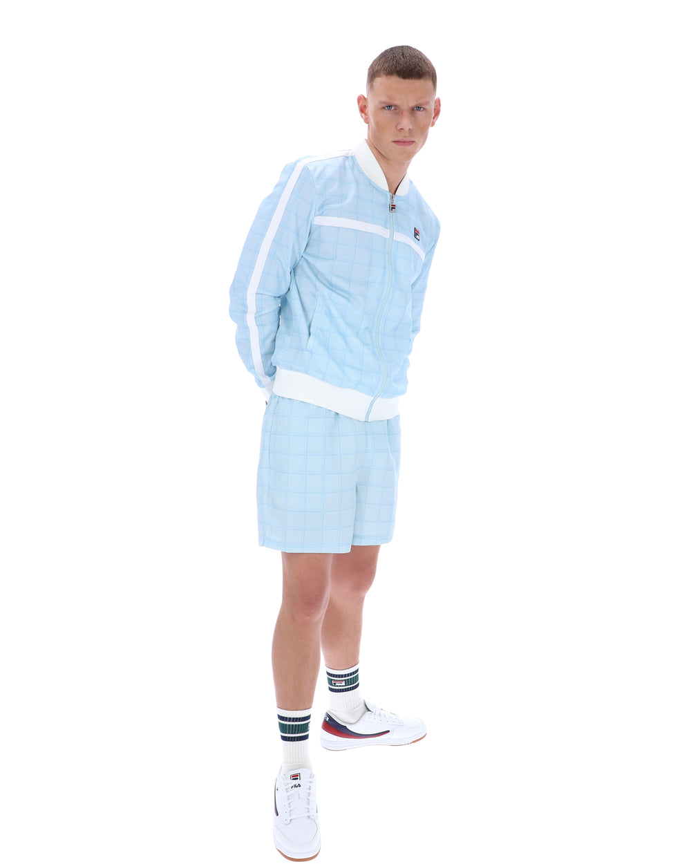 Man wearing a light blue tracksuit with white accents on a white background