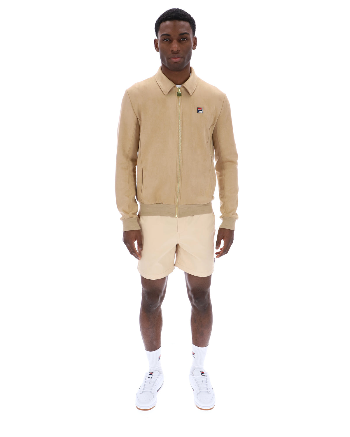 Man wearing a beige tracksuit Jacket with a small FILA logo on the chest, paired with cream shorts, on a white background