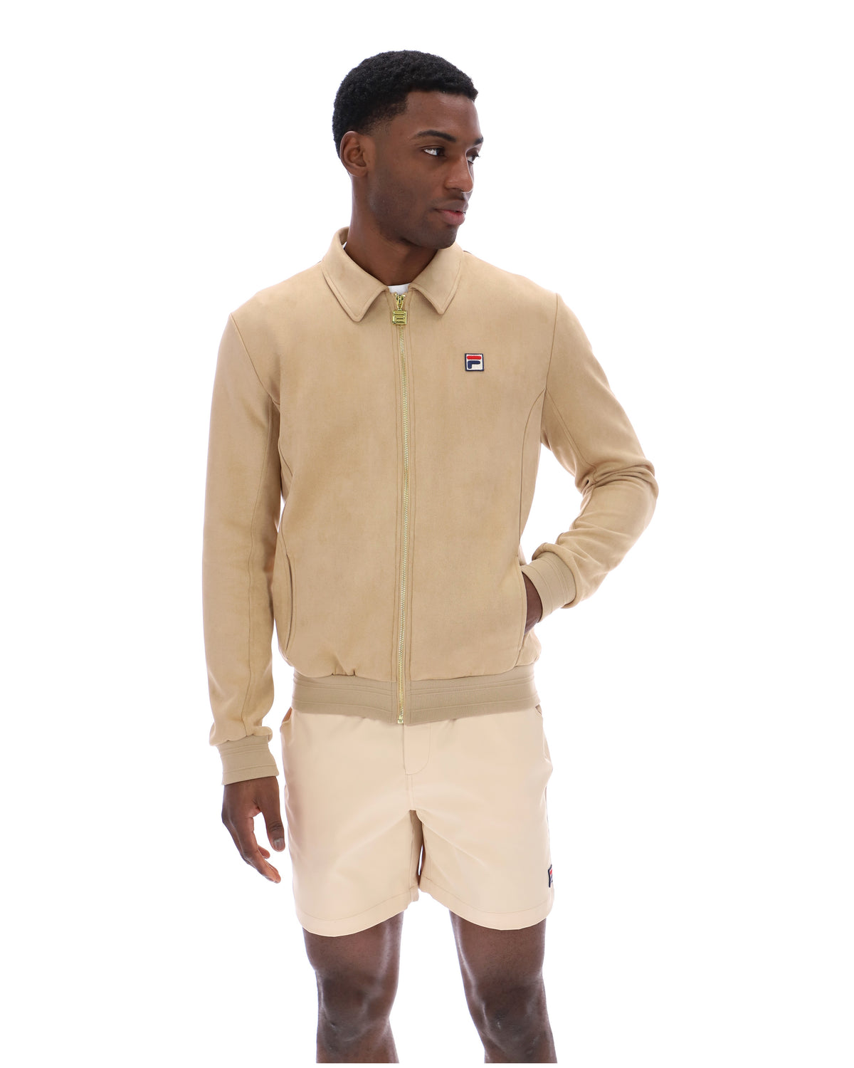 Man wearing a beige tracksuit Jacket with a small FILA logo on the chest, paired with cream shorts, on a white background