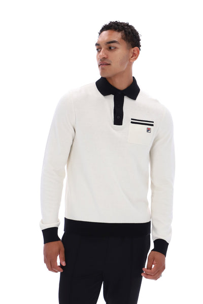 A man wearing a long-sleeve polo shirt in off-white with a black collar, black cuffs, and a black chest stripe detail, paired with black trousers, against a plain white background.