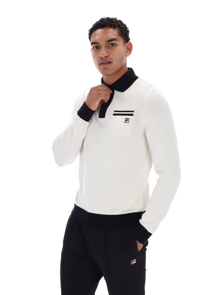 A man wearing a white long-sleeve knit polo shirt with a black collar and cuffs, featuring a small red, white, and blue Fila logo on the left chest, paired with black sweatpants against a white background.