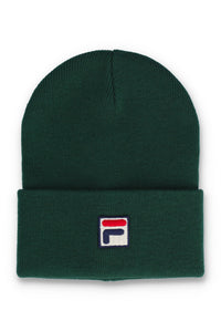 A dark green ribbed knit beanie hat with a folded cuff, featuring a small embroidered Fila logo patch on the front.