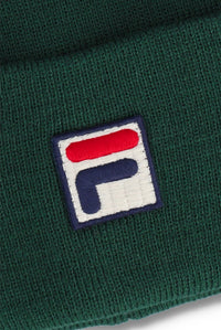 Close-up of a dark green ribbed knit beanie with a square embroidered Fila logo patch on the front.