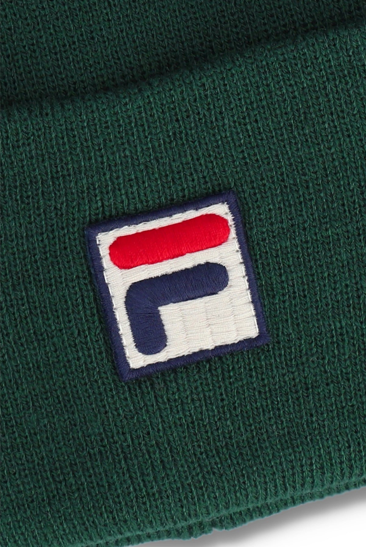 Close-up of a dark green ribbed knit beanie with a square embroidered Fila logo patch on the front.